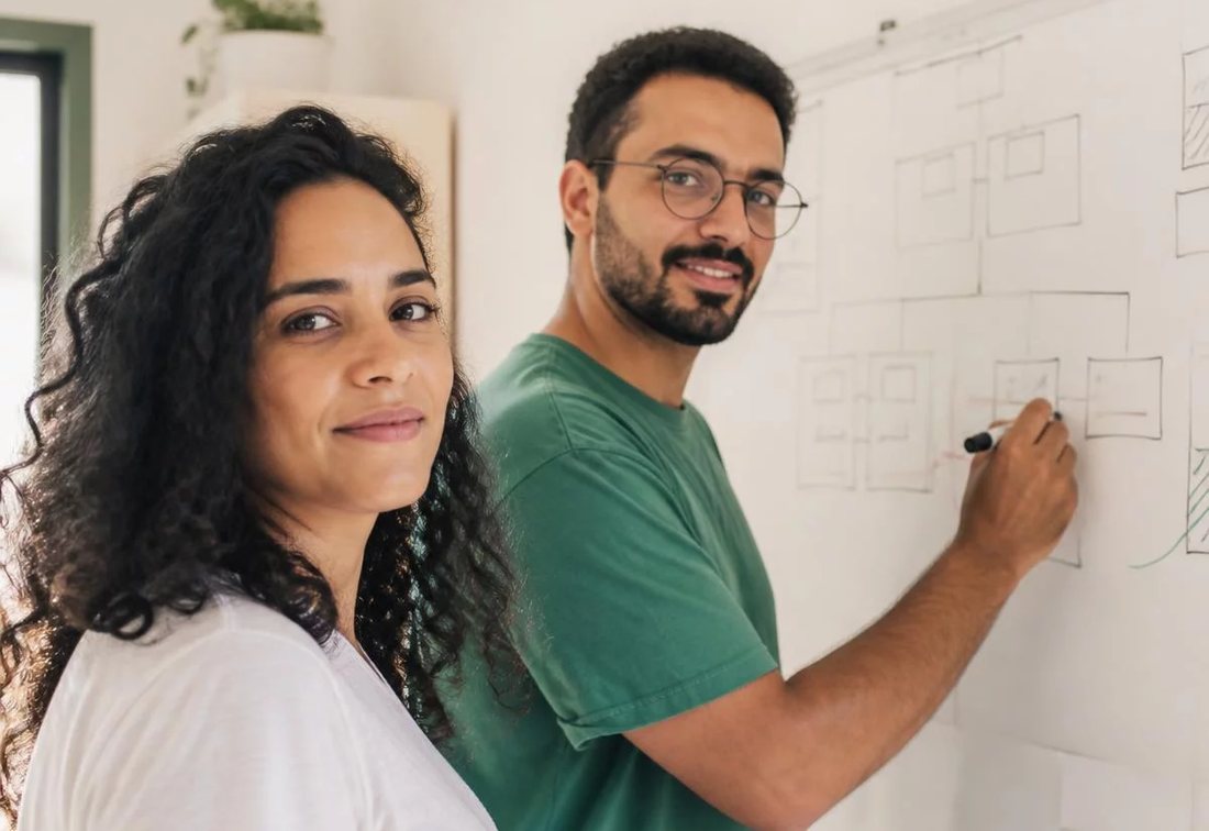 Dupla desenhando no quadro branco a estrutura de uma tese